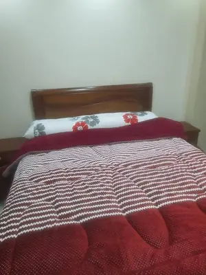 a bed with a red and white comforter on it at عبق التاريخ هاوس in Rujm al Ḩāwī