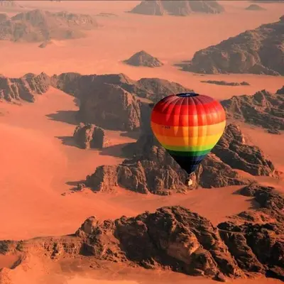 a colorful hot air balloon flying over the desert at Desert Sands Camp Wadi Rum in Wadi Rum
