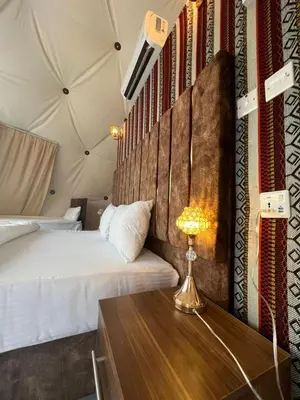 a bedroom with a bed and a table with a lamp at Suleman Bedouin Life Camp in Wadi Rum