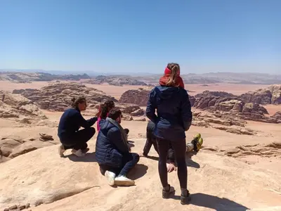 a group of people standing on a rock in the desert at Wadi Rum Hiking &camp in Wadi Rum