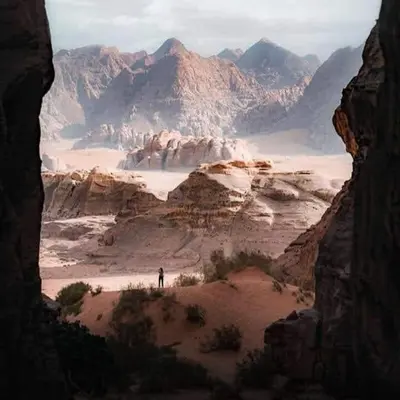 a person standing in a desert with mountains in the background at Wadi Rum Hiking &camp in Wadi Rum