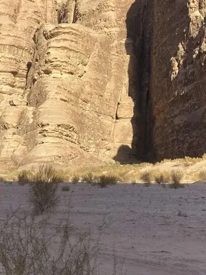 a rock cliff in the middle of a desert at Wadi rum fasial camp in Wadi Rum
