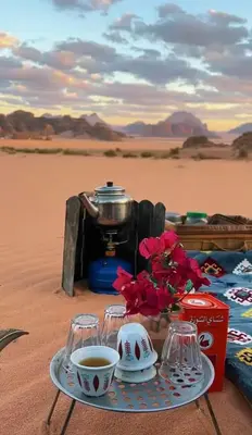a tray with a cup of coffee and flowers on a table in the desert at Wadi rum fasial camp in Wadi Rum