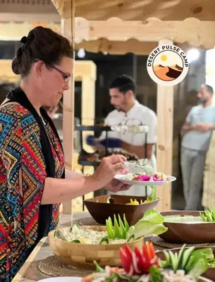 a woman holding a plate of food on a buffet at RUM BULSE BUBBLE lUXURY CAMP in Disah