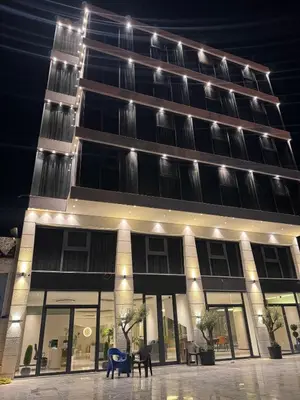a large building with chairs in front of it at night at Ailana Hotel in Aqaba