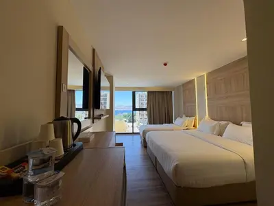 a hotel room with two beds and a large window at Ailana Hotel in Aqaba
