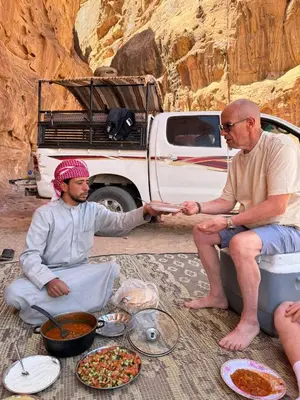 two men sitting in front of a truck with food at Ruby Orbit Wadi Rum in Wadi Rum