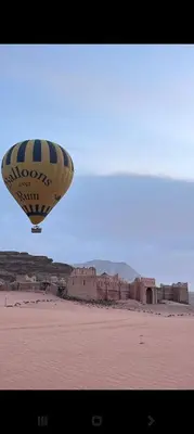 a hot air balloon flying in the sky over a desert at Wadi Rum Sand moon Camp &Tour in Wadi Rum