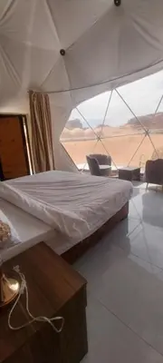 a bed in a tent with a view of the desert at Wadi Rum Sand moon Camp &Tour in Wadi Rum