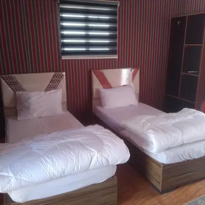 two twin beds in a room with red walls at Wadi Rum Sand moon Camp &Tour in Wadi Rum