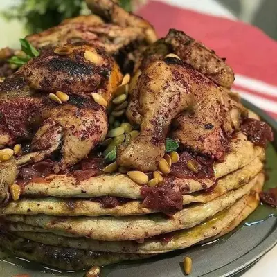 a stack of chicken pancakes with peanuts on a plate at 77 apartment in Abū aş Şalīḩ