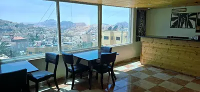 a dining room with a table and chairs and a large window at Rafiki Hostel in Wadi Musa