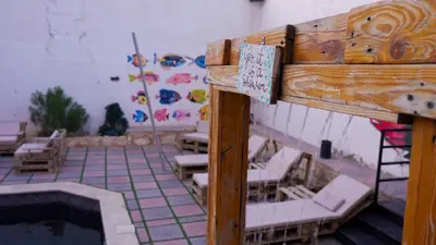 a room with a pool and chairs and a sign at Rafiki Hostel in Wadi Musa