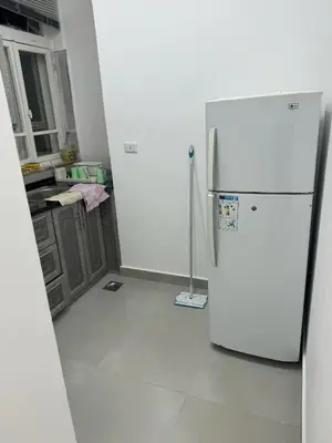 a kitchen with a white refrigerator in a room at Ahlam Apartments in Amman
