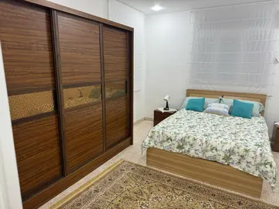a bedroom with a bed and a large wooden closet at Ahlam Apartments in Amman