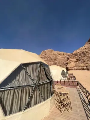 a couple of tents with chairs in the desert at Whispers of Night Camp in Jurf ad Darāwīsh
