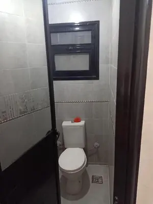 a bathroom with a toilet and a window in it at غباوي موتل in Az Zarqa