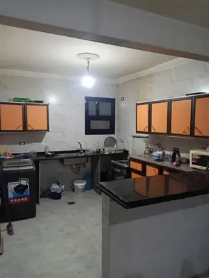 a large kitchen with orange cabinets in a room at غباوي موتل in Az Zarqa