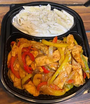 a black tray of food with chicken and vegetables at غباوي موتل in Az Zarqa