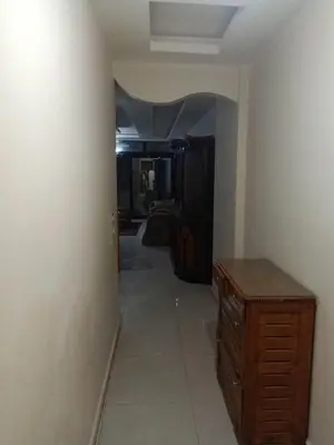 a hallway with a wooden dresser and a room at غباوي موتل in Az Zarqa