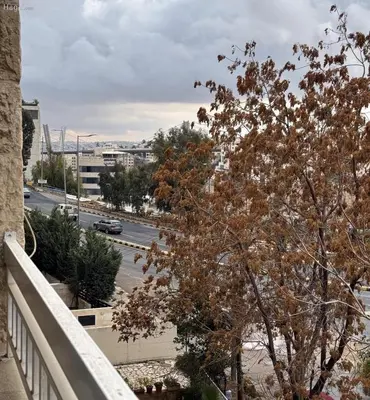 a tree on a balcony with a view of a street at شقة مفروشة للايجار مميزه هادئه امنه ذات اطلاله رائعه in Amman
