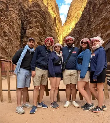 a group of people posing for a picture in front of a mountain at Sands of time desert camp in Wadi Rum