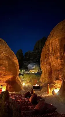 a rock cave with pillows on the beach at night at في اصحراء المريخ في وادي رم in Jurf ad Darāwīsh