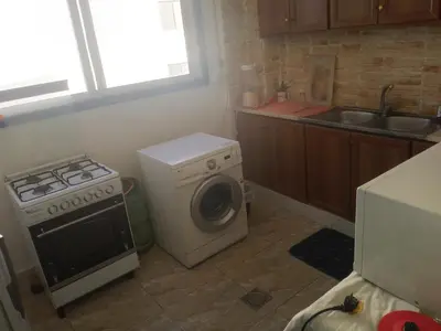 a kitchen with a stove and a washing machine at Sindbad Apartment in Jurf ad Darāwīsh