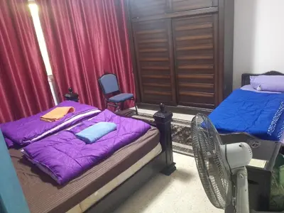 a bedroom with two beds with purple sheets and a fan at Sindbad Apartment in Jurf ad Darāwīsh