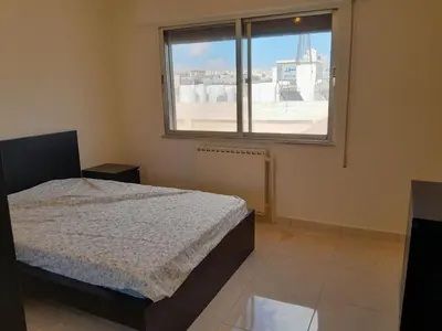 a bedroom with a bed and a large window at Cosy family apartment in Amman in Amman