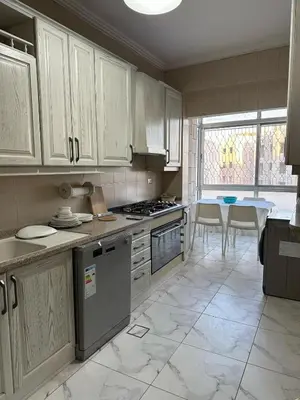 a kitchen with white cabinets and a table in it at Cosy family apartment in Amman in Amman