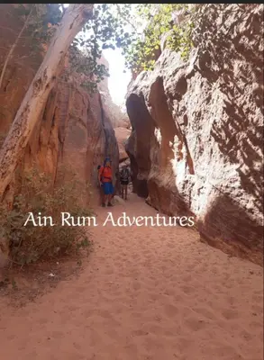 a group of people standing on a dirt path in a canyon at مغامرات عين رم in Wadi Rum