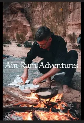 a man cooking food over a camp fire at مغامرات عين رم in Wadi Rum