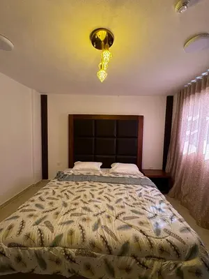 a bedroom with a large bed and a chandelier at Camel Dive Club By The Sea Inn in Jurf ad Darāwīsh