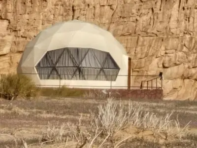 a building with a domed roof next to a stone wall at Eram camp in Jurf ad Darāwīsh