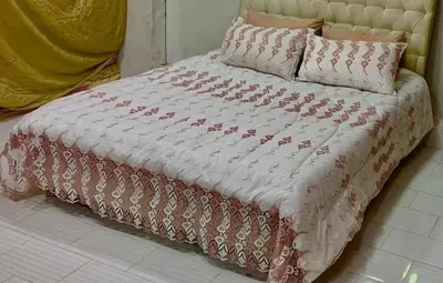 a bed with a red and white comforter and pillows at bong chalet in Amman