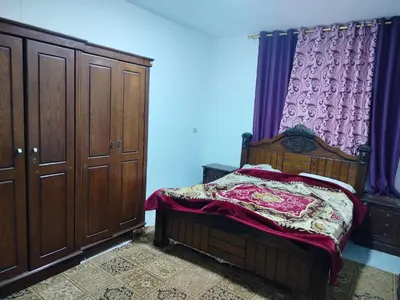 a bedroom with a bed and a dresser with purple curtains at شقق ابو يزن عجلون بالقرب من محمية عجلون in Ajloun