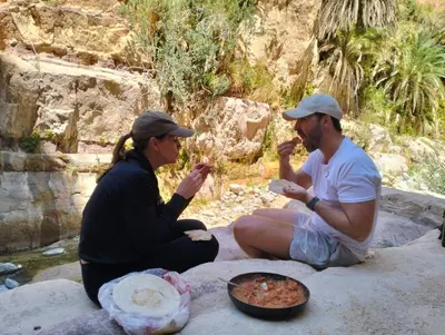 a man and a woman sitting on a rock eating food at Dana Village experience hotel in Dana