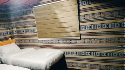 a bedroom with two beds and a wall covered in wallpaper at Dana Village experience hotel in Dana