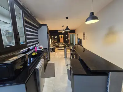 a kitchen with black counter tops and a living room at Rainbow Retreat - 2BR in the heart of Old Amman in Amman