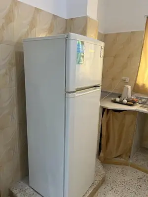 a white refrigerator in a kitchen with a table at Altamem apartment in Um Qeis