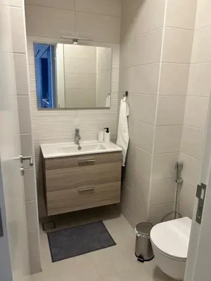 a bathroom with a sink and a mirror and a toilet at Ayla Beach Apartment Azure 1522 Families only in Aqaba