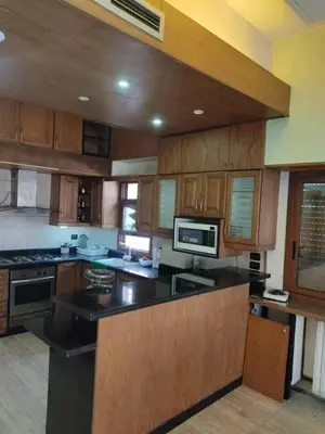 a large kitchen with wooden cabinets and a microwave at جرف العز هاوس in Jurf ad Darāwīsh