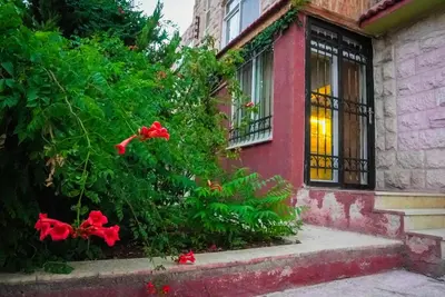 a house with red flowers in front of a window at Family-Friendly Garden Stay in Jurf ad Darāwīsh