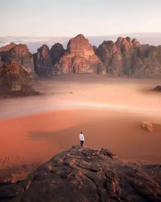 a man standing on top of a rock in the desert at Wadi rum ail camp in Wadi Rum