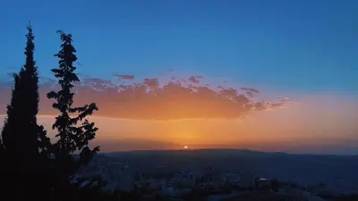 a sunset with the sun setting over a city at شقق ڤيڤا - viva Apartments in Amman