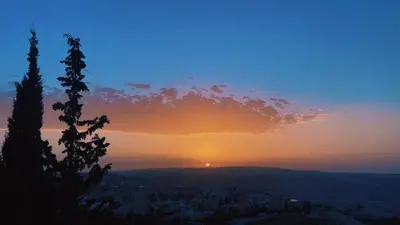 a sunset with the sun setting over a city at شقق ڤيڤا - viva Apartments in Amman