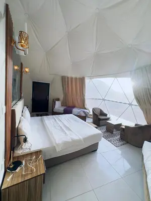 a bedroom with a large bed and a large window at RUM FLORAA LUXURY CAMp in Wadi Rum