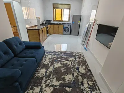 a living room with a blue couch and a kitchen at Furnished apartment - Irbid in Irbid