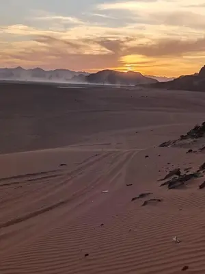 an empty desert with the sunset in the background at Wasan Camp Wadi Rum in Wadi Rum